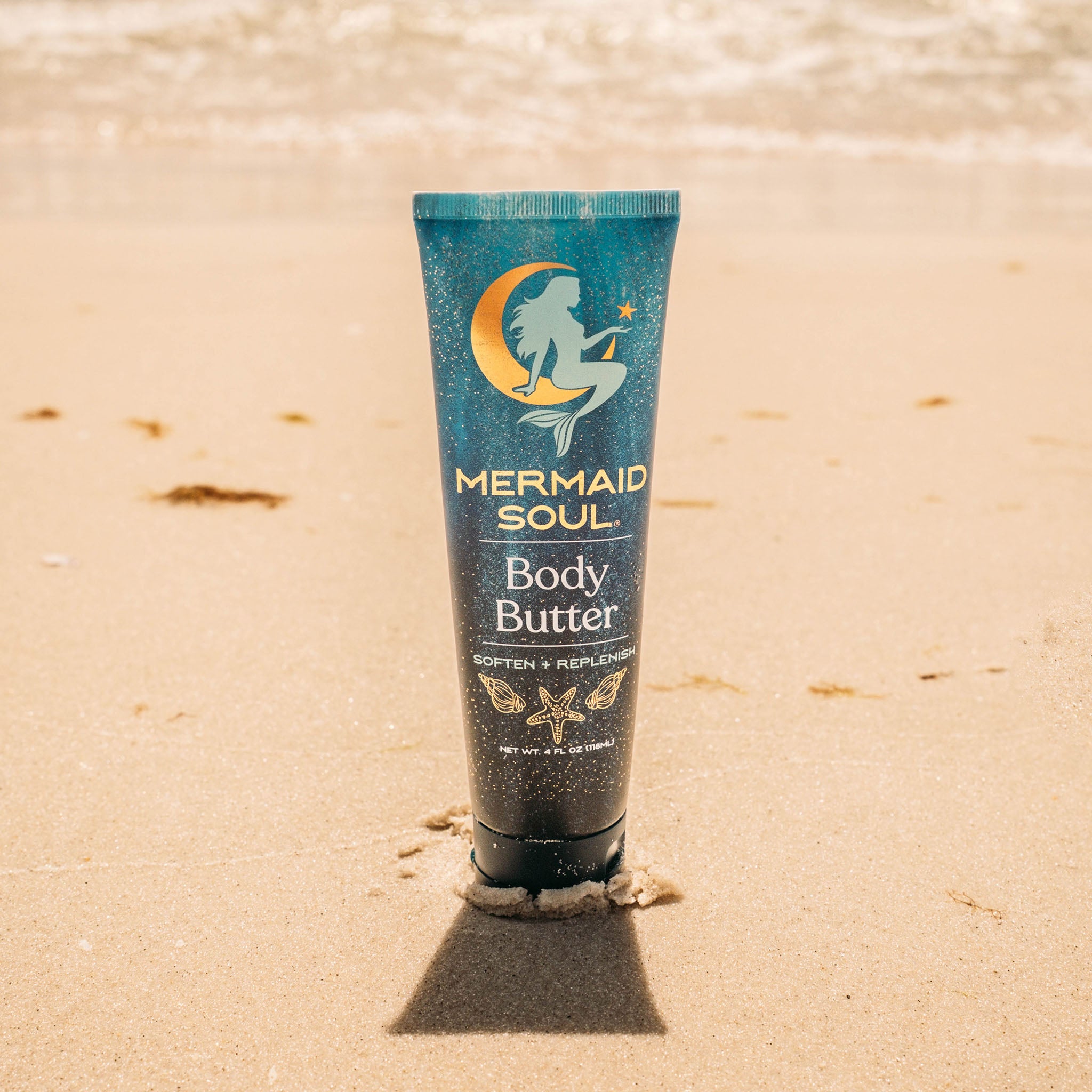 Tube of Mermaid Soul Body Butter on a sandy beach