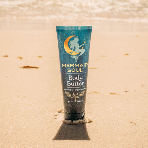 Tube of Mermaid Soul Body Butter on a sandy beach