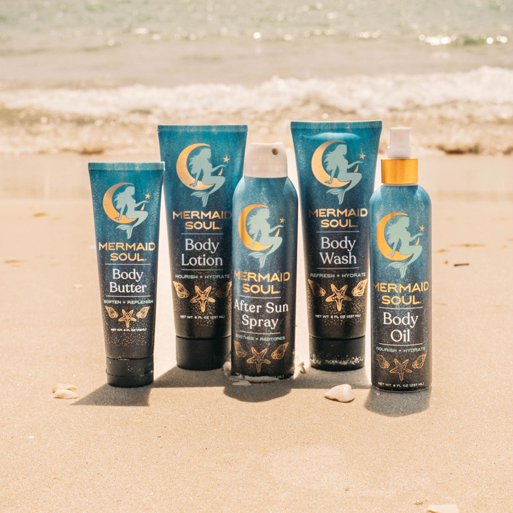 Collection of Mermaid Soul body care products on a sandy beach.